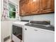 Bright laundry room with white washer and dryer, wood cabinets, and a window at 6360 Lakeview Ter, Douglasville, GA 30135