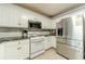 Bright kitchen features stainless steel refrigerator and gas stove along with white cabinetry at 1623 Pratt Rd, Covington, GA 30014