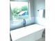 Relaxing bathroom featuring a soaking tub, a stylish faucet, and a view of the outdoors at 2668 Memorial Se Dr, Atlanta, GA 30317