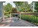 A wooden back deck featuring a grill, overlooking the green, landscaped backyard at 115 Windover Ct, Roswell, GA 30075