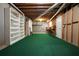 Unfinished basement with exposed ceiling, green carpet, and a built-in bookcase at 115 Windover Ct, Roswell, GA 30075