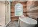 Bathroom featuring soaking tub, glass shower, wood accent wall, decorative window and patterned tile floor at 115 Windover Ct, Roswell, GA 30075