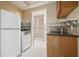 A compact kitchen area featuring a stove, refrigerator, and sink with marble countertop next to a bathroom at 115 Windover Ct, Roswell, GA 30075