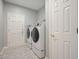 Laundry room with a washer and dryer, tile floors, neutral gray paint, and white doors at 115 Windover Ct, Roswell, GA 30075