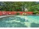 Inviting backyard pool surrounded by mature trees and a red privacy fence at 115 Windover Ct, Roswell, GA 30075