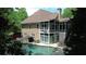 Backyard view of a home's screened porch and refreshing pool surrounded by lush greenery at 115 Windover Ct, Roswell, GA 30075