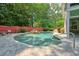 Backyard view of the pool with a rock waterfall feature and red fence at 115 Windover Ct, Roswell, GA 30075