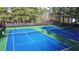 Community tennis courts with blue and green surfaces and forest perimeter at 115 Windover Ct, Roswell, GA 30075