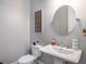 Powder room featuring a modern pedestal sink, round mirror, and updated toilet at 623 Brennan Dr, Decatur, GA 30033