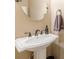 Elegant bathroom sink with pedestal, ornate faucet and a round mirror enhancing the warm, neutral wall color at 5767 Wembley Dr, Douglasville, GA 30135
