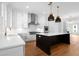 Bright kitchen with stainless steel appliances, white cabinets, an island with quartz counters, and hardwood floors at 205 Mayfair Ct, Alpharetta, GA 30009