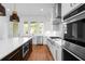 Open kitchen features stainless steel appliances, white cabinets, a dark island with quartz counters, and hardwood floors at 205 Mayfair Ct, Alpharetta, GA 30009