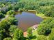 Aerial view of a serene lake surrounded by lush greenery and trees, showing a gazebo on its bank at 2766 Wander Ln, Alpharetta, GA 30022