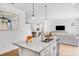 Kitchen island featuring stainless steel sink, granite countertops, and pendant lighting with view to living spaces at 1405 Windance Lake Dr, Loganville, GA 30052