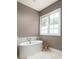 Bright bathroom with soaking tub by window plus stool and faux fur rug creates a charming space at 385 Anders N, Chattahoochee Hills, GA 30268