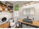 Bright laundry room with modern washer, dryer, sink, and open shelving for storage at 385 Anders N, Chattahoochee Hills, GA 30268