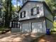 Two-story home with a two-car garage, black trim, and mature trees surrounding the property at 4064 Panola Woods Dr, Stonecrest, GA 30038