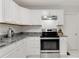 White kitchen with stainless steel appliances, white cabinets, gray counter tops and white tile floors at 553 Collingwood Dr, Decatur, GA 30032
