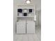 Bright laundry room with overhead cabinets, open storage shelves, white washer and dryer at 553 Collingwood Dr, Decatur, GA 30032