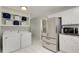 Bright laundry room with stainless steel refrigerator, white cabinets and white washer and dryer at 553 Collingwood Dr, Decatur, GA 30032