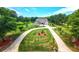 Stunning aerial view of a home with circular driveway, lush lawn, and beautifully landscaped grounds surrounded by mature trees at 100 Marshas Vineyard, Hampton, GA 30228