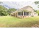 View of a screened in porch and brick home, surrounded by lush greenery and a well-kept lawn at 100 Marshas Vineyard, Hampton, GA 30228