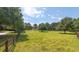A vast green lawn stretches out behind a sturdy wooden fence, offering privacy and a picturesque view of mature trees at 100 Marshas Vineyard, Hampton, GA 30228