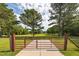 View through a gate of a large, grassy yard with scattered trees, offering a serene and private outdoor space at 100 Marshas Vineyard, Hampton, GA 30228
