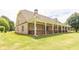 Side view of a brick home showcasing its expansive covered porch and well-maintained lawn at 100 Marshas Vineyard, Hampton, GA 30228