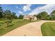 A well-manicured lawn with mature trees and a long driveway leading to a charming brick home, creating a welcoming entrance at 100 Marshas Vineyard, Hampton, GA 30228