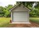 Garage with white siding and a closed roll-up door, with a potted cactus to the side at 100 Marshas Vineyard, Hampton, GA 30228