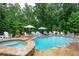 Beautiful backyard pool area with a hot tub and plenty of seating surrounded by lush trees at 7131 Ridge Rd, Hiram, GA 30141