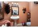 Charming powder room with a pedestal sink, peach walls, decorative mirror and unique wall decor at 7131 Ridge Rd, Hiram, GA 30141