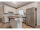 Well-lit kitchen featuring white cabinets, stainless steel refrigerator, center island, and tile floors at 134 N Alexander St, Buford, GA 30518