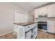 Updated kitchen featuring white cabinets, a center island with seating, tile floors, and stainless steel oven at 134 N Alexander St, Buford, GA 30518