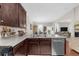 View of the kitchen with stainless dishwasher, dark cabinetry, dining table and chairs, plus living room in the background at 3504 Castleberry Village Cir # 36, Cumming, GA 30040
