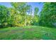 A backyard with lush green grass, enclosed by a chain-link fence, surrounded by mature trees at 4457 Lincoln Jones Rd, Ellenwood, GA 30294