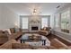 Cozy living room featuring a fireplace, plush seating, a ceiling fan, and abundant natural light at 290 Bluff Oak Dr, Roswell, GA 30076