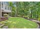 Beautifully landscaped backyard features a lush lawn surrounded by mature trees and garden beds at 335 S Satinwood Pl, Roswell, GA 30076