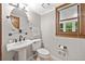 Traditional bathroom features a pedestal sink, oval mirror, and window with natural light at 335 S Satinwood Pl, Roswell, GA 30076
