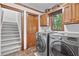 A laundry room featuring a modern washer and dryer, wooden cabinets, and tile flooring at 335 S Satinwood Pl, Roswell, GA 30076