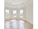 This bedroom features a tray ceiling, three windows, and hardwood floors at 5121 Hope Sw Ct, Lilburn, GA 30047