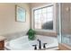 A bathtub with tile surround and decorative window makes this bathroom a relaxing retreat at 5250 Villa Lake Ct, Suwanee, GA 30024
