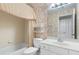Traditional bathroom featuring a tub with shower, patterned wallpaper, and a white vanity at 5250 Villa Lake Ct, Suwanee, GA 30024