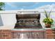 Stainless grill on a brick stand surrounded by a tiled counter and lush landscaping at 5250 Villa Lake Ct, Suwanee, GA 30024