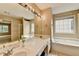 The main bath features a tub and separate shower, double sinks and a large window at 12060 Carriage Park Ln, Duluth, GA 30097