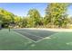 A tennis court with an outdoor green court and nets surrounded by lush green trees at 408 Coleraine Se, Smyrna, GA 30080