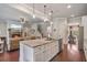 Open kitchen with granite island, pendant lights, stainless appliances, and dark hardwood floors adjacent to living room at 3352 Stone Point Way, Buford, GA 30519