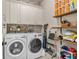 Well-organized laundry room features a brick backsplash, shelving, front-load washer, and front-load dryer at 3352 Stone Point Way, Buford, GA 30519