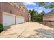 A brick house exterior showing a two-car garage, driveway, and side yard at 8295 St Marlo Fairway Dr, Duluth, GA 30097